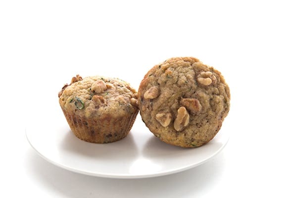 Two keto zucchini muffins on a white plate with a white background