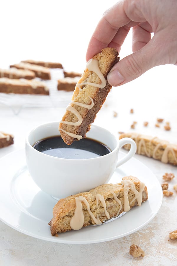 A hand dipping some keto biscotti into a cup of coffee