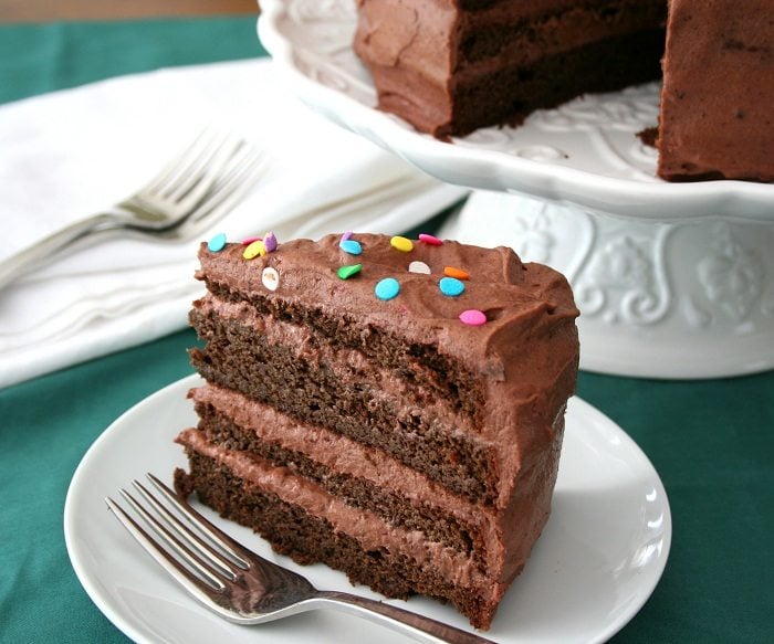 slice of gluten-free chocolate cake with chocolate sour cream frosting and sprinkles on top