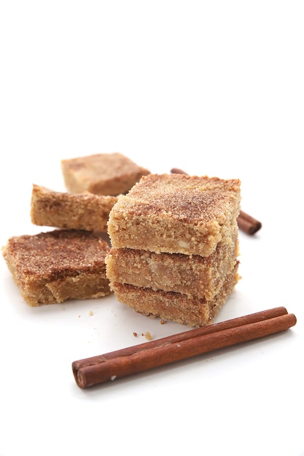 Snickerdoodle blondies in a stack with cinnamon sticks in front