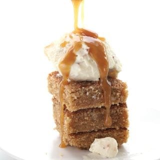 Drizzling sugar free caramel sauce over a stack of snickerdoodle blondies with some ice cream on top.