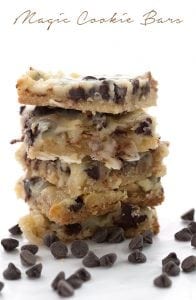 Low Carb Magic Cookie Bars in a stack with chocolate chips around them.