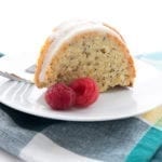 A slice of low carb lemon poppyseed cake on a white plate with a plaid napkin