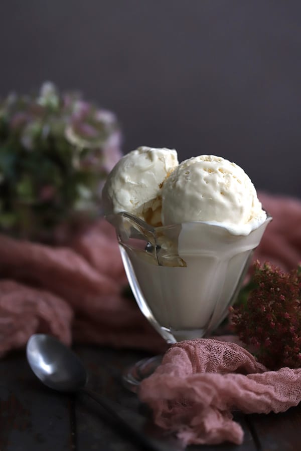 A glass of homemade keto ice cream with pink fabric and flowers around it