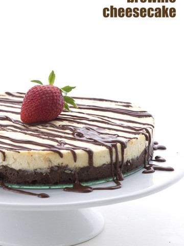 Low Carb and Gluten-Free brownie cheesecake drizzled with sugar free chocolate sauce sitting on a white cake stand