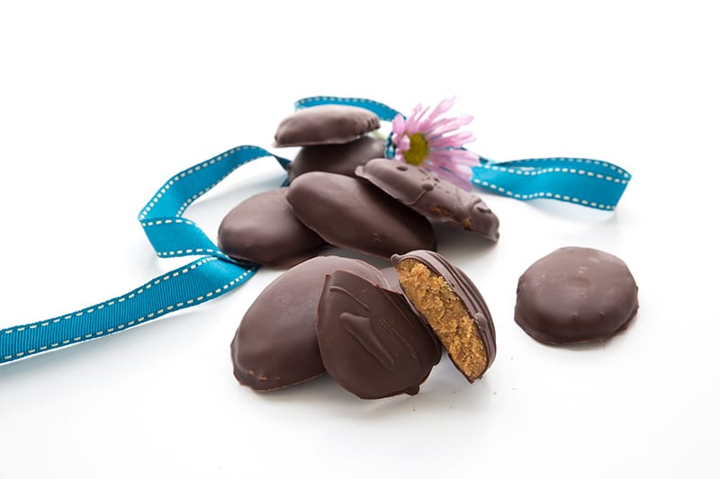 Peanut butter eggs in a pile with ribbons and flowers.