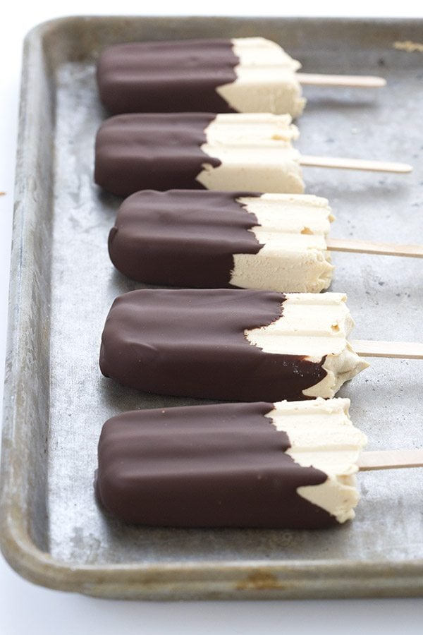healthy peanut butter popsicles dipped in sugar-free chocolate in a row on a cookie sheet. 