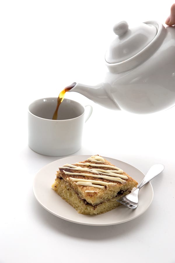 Slice of sugar-free cinnamon roll coffee cake with coffee being poured into a mug.