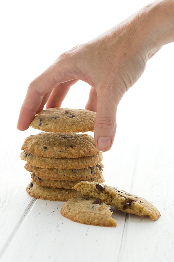 hand picking up a low carb grain free Chocolate Chip Cookie from a stack underneath it