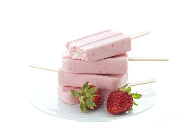 A stack of keto strawberry cheesecake popsicles, and a bite take out of the top one.