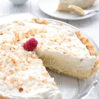 A sugar free coconut cream pie with a slice taken out of it.