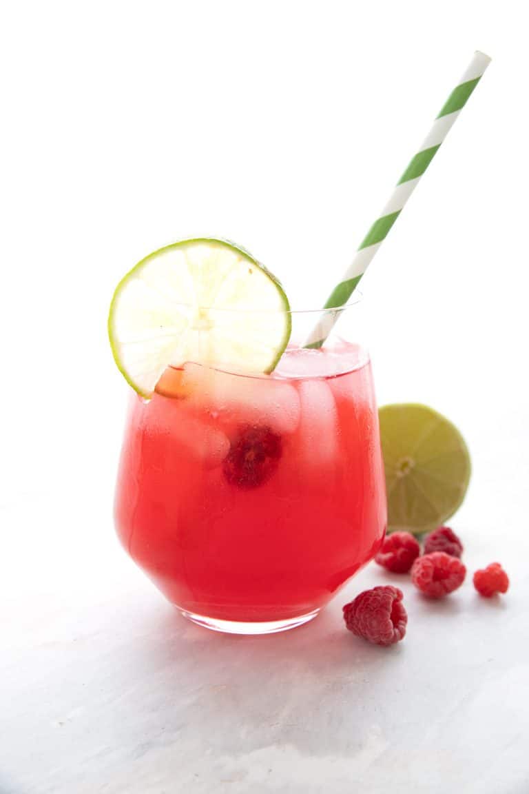 A glass of raspberry limeade with a striped green straw.