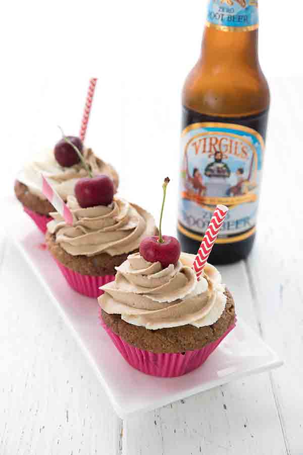 Three keto root beer float cupcakes on a white plate, with a bottle of sugar-free root beer in the background