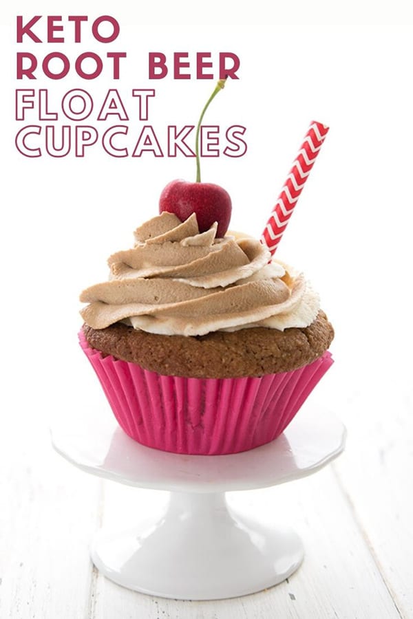 Titled image of a keto root beer float cupcake on a white cake stand. The cupcake has a cherry on top and a red striped straw stuck into the frosting.