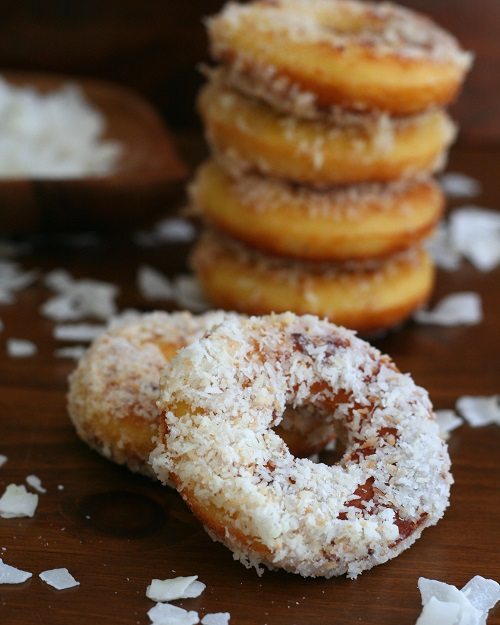 a stack of fried coconut flour donuts topped with shredded coconut