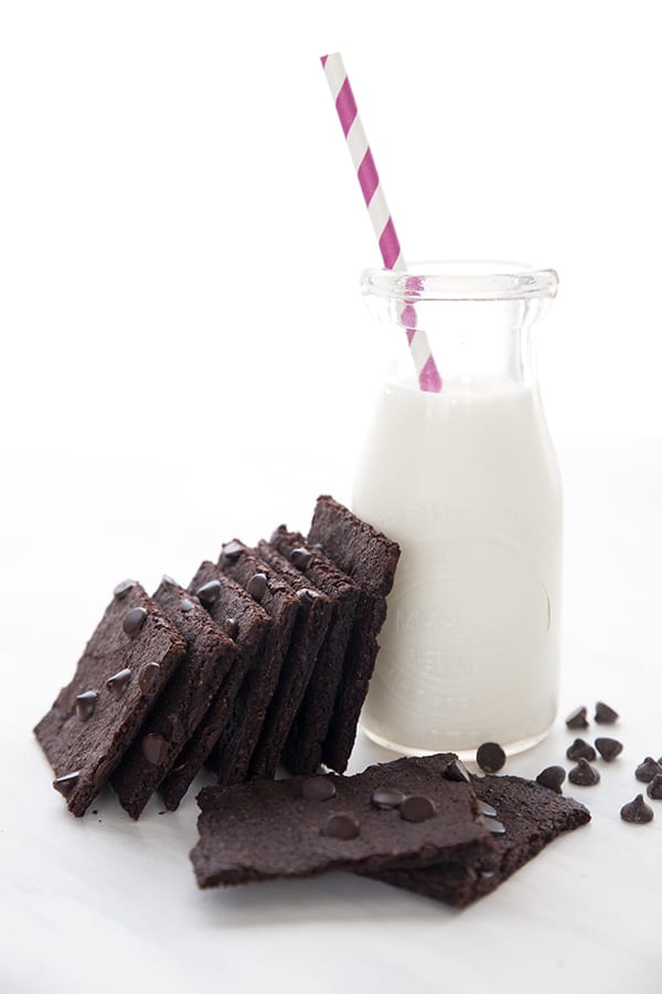 Brownie bark stacked against a glass of milk with a pink striped straw