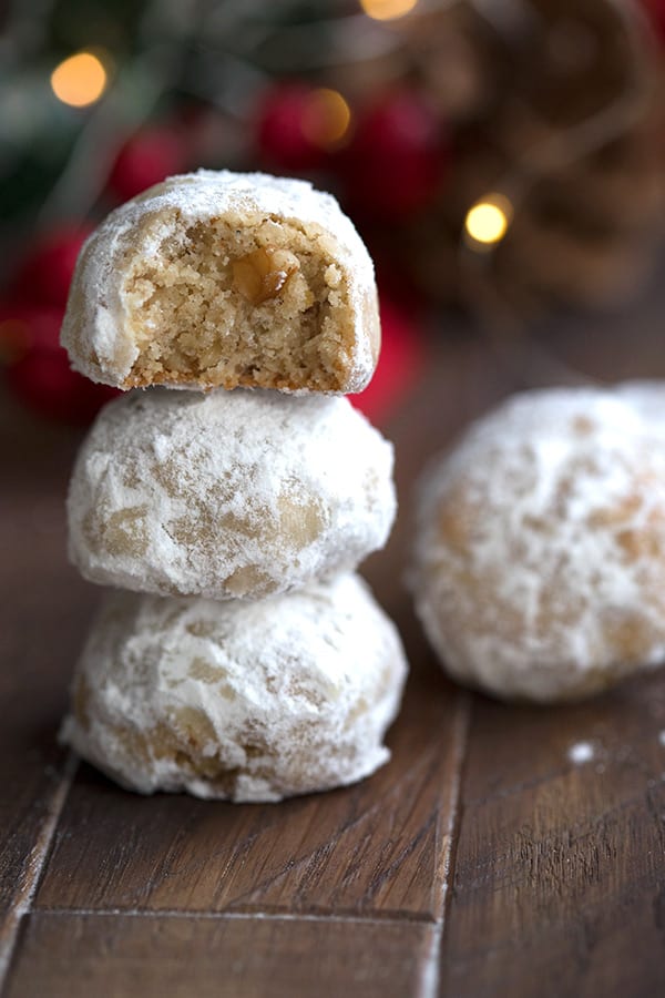 Keto snowball cookies in a stack with a bite taken out of the top cookie. 