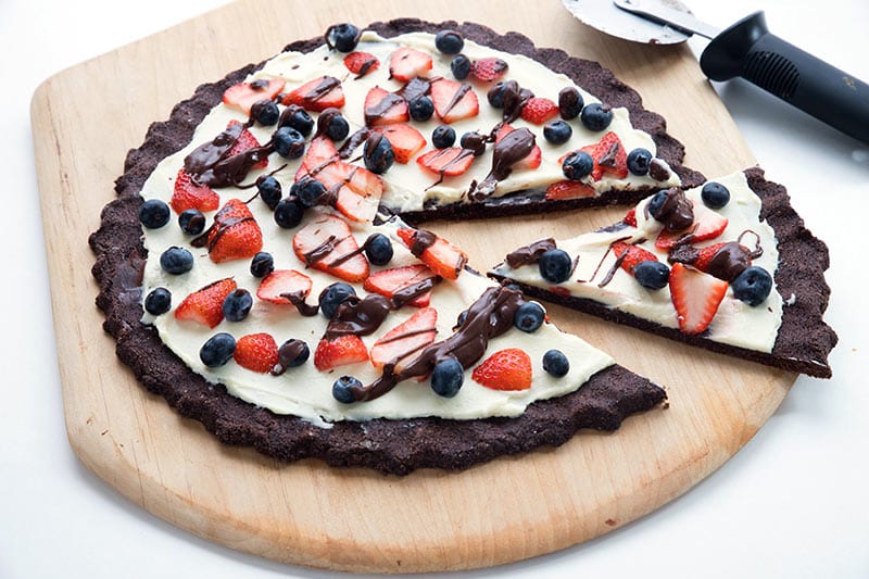 Chocolate Cookie Pizza with a slice cut out and a pizza wheel