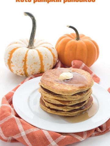 Easy keto pumpkin pancakes on a white plate with pumpkins in the background.