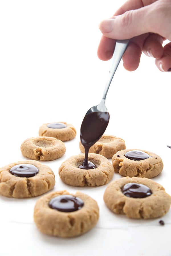 Spooning sugar free chocolate ganache into low carb peanut butter blossoms