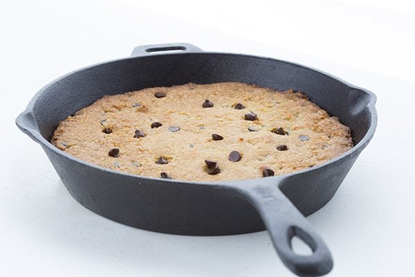 Keto chocolate chip skillet cookie in a black skillet on a white background. 