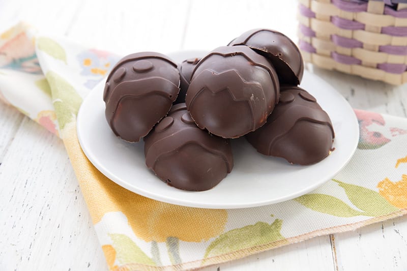 A pile of keto chocolate Easter eggs on a white plate over a bright colored napkin