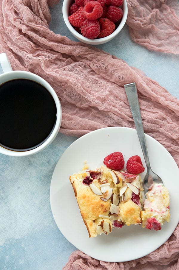 Raspberry Cream Cheese Coffee Cake on a plate with a cup of coffee