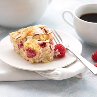 A slice of cream cheese coffee cake on a plate with raspberries