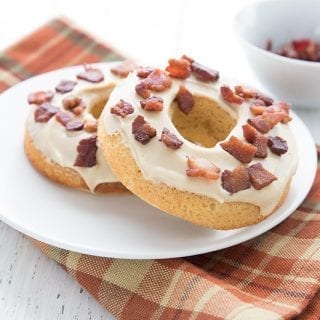 A white plate with two keto maple bacon donuts over a plaid napkin