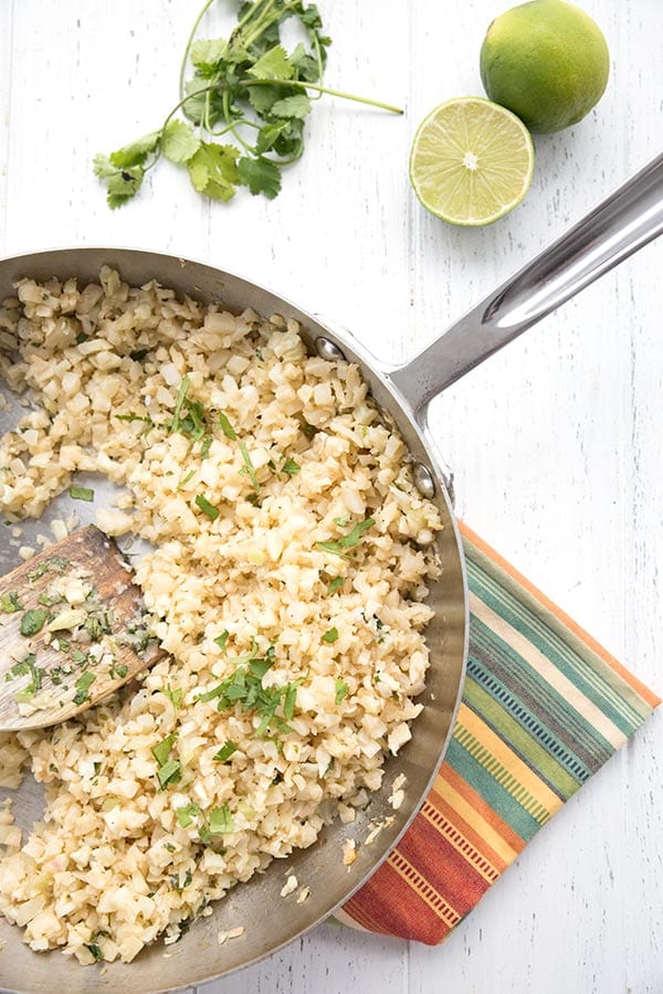 Top down photo of cilantro lime cauliflower rice on a white table. 
