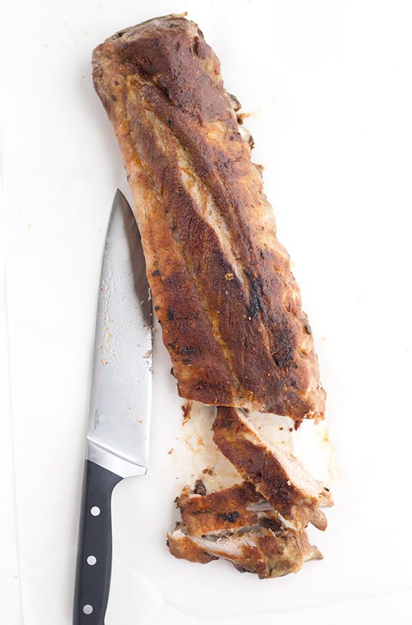A long rack of dry rub spare ribs with a knife