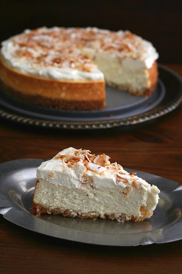 Sugar Free Coconut Cheesecake with a slice on a plate and the rest of the cake in the background