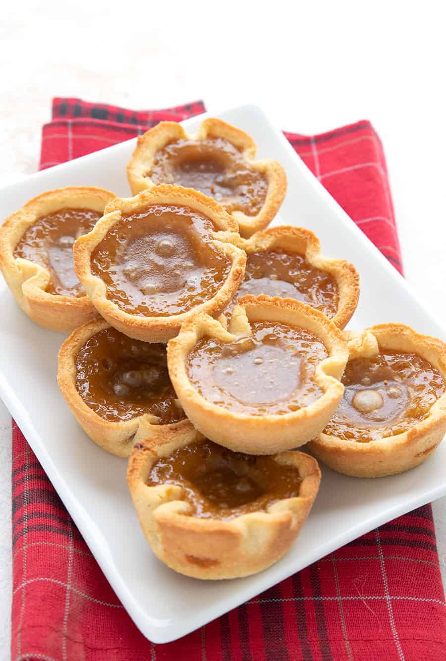 A white tray filled with keto butter tarts over a red plaid napkin