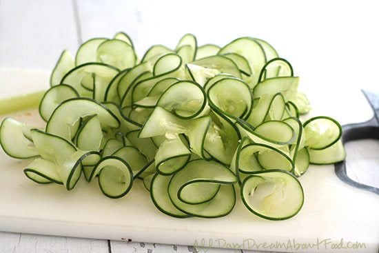 Cucumber noodles in a pile on a white cutting board