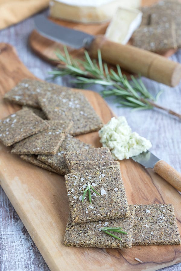 Nut-free keto crackers on a wooden cutting board with cheese in the background