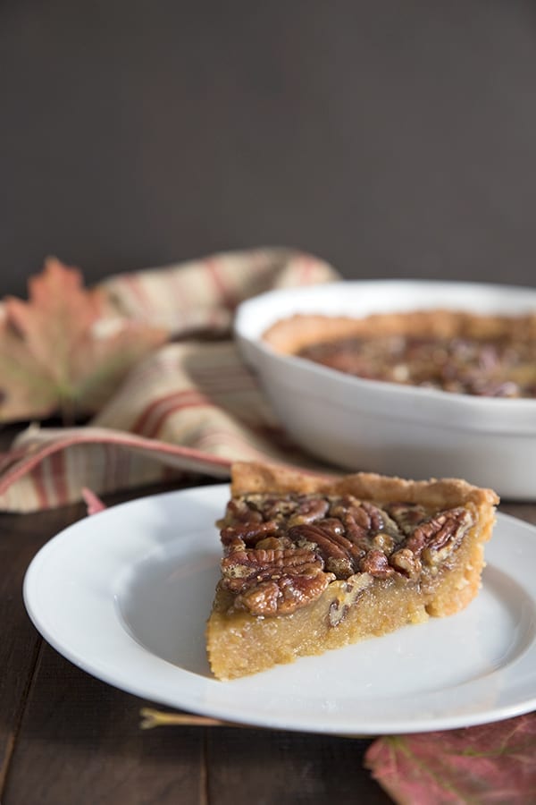 A slice of low carb pecan pie with the whole pie in the background