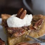 Close up of a slice of sugar free pecan pie on a white plate with a fork