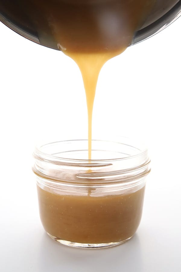 Pouring caramel sauce from the pan into a jar