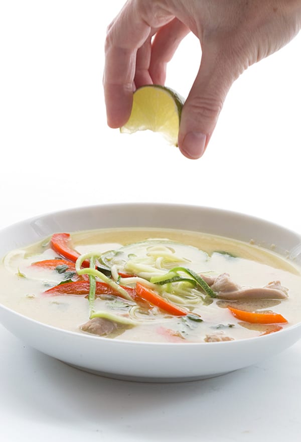 Squeezing a wedge of lime over keto thai chicken soup