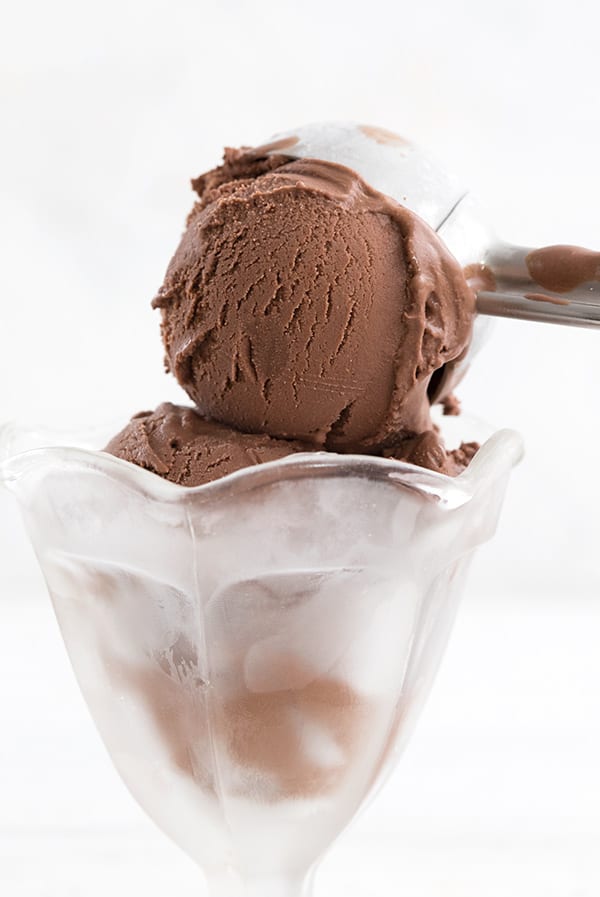 An ice cream scoop putting rich death by chocolate ice cream into a glass ice cream dish