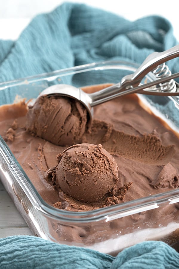 Dark chocolate keto ice cream being scooped out of a glass container