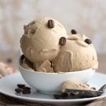 A bowl of keto coffee ice cream with coffee beans on a brown patterned napkin
