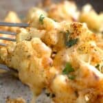 Titled Pinterest image of cheesy roasted cauliflower being lifted from a pan on a metal spatula.