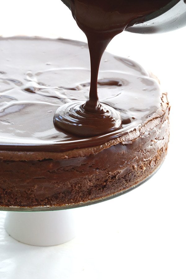 Pouring sugar-free chocolate ganache over low carb chocolate cheesecake