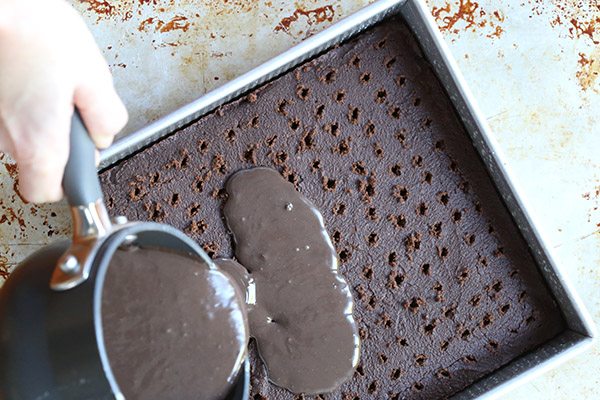Pouring low carb chocolate peppermint pudding into a delicious grain-free mocha poke cake.