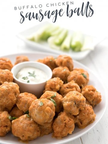 A plate of keto sausage balls with ranch dipping sauce in the center. There is a plate of celery in the background