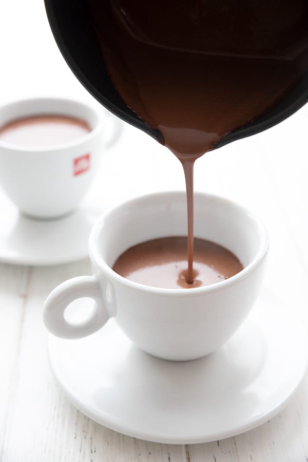 Pouring keto drinking chocolate from a pot into a mug.