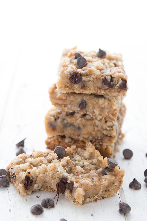 A stack of keto carmelita bars with two in front and chocolate chips all around.