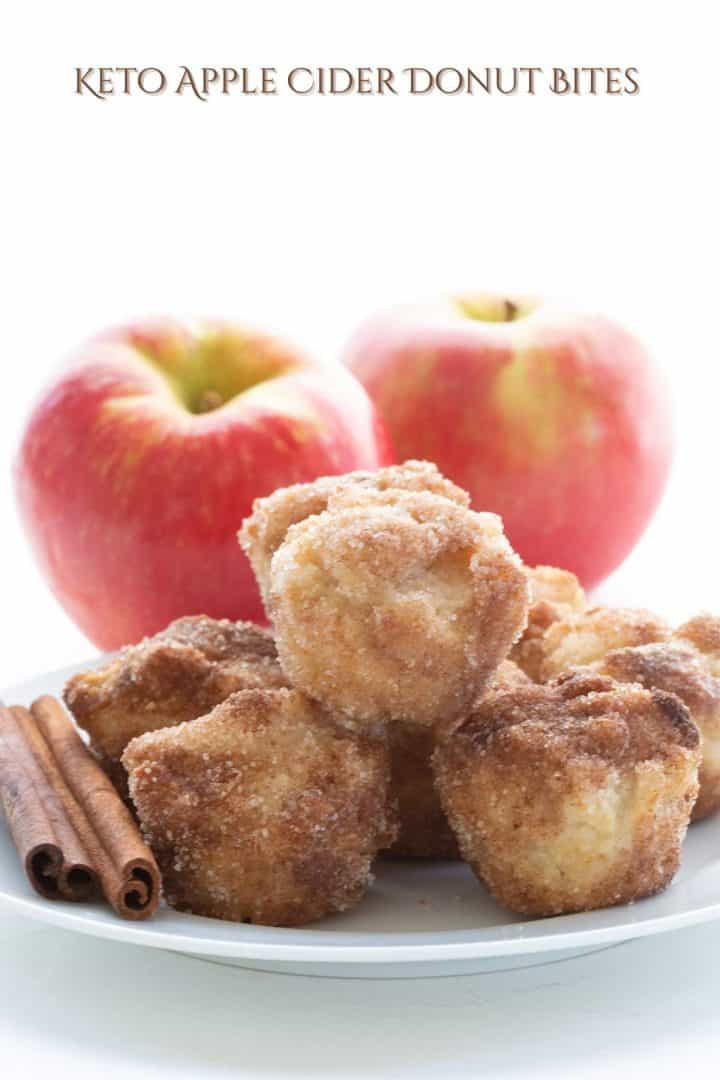 A plate of keto apple cider donut bites in front of two apples. 