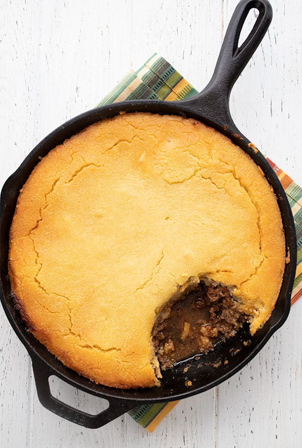 Top down image of keto tamale pie in a cast iron skillet on a white table.